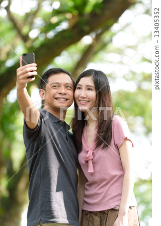 Chinese couple talking their own picture with their handphone 13405352