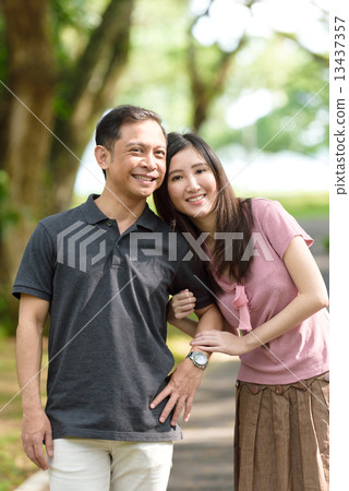 Chinese couple holding hands walking in a park 13437357