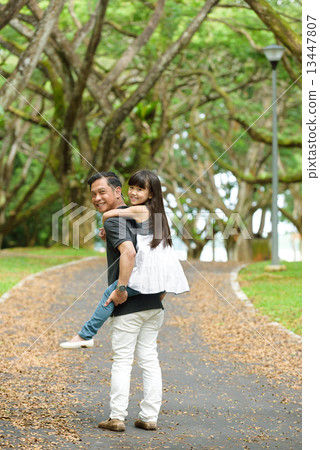 Chinese father piggy back daughter in the park 13447807