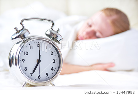 alarm clock and sleeping young woman 13447998