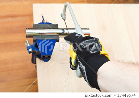 plumber sawing plumbing drain pipe gripped in vice 13449574