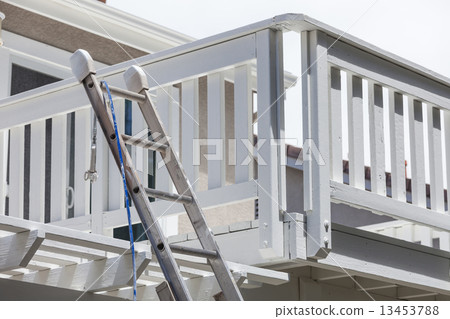 Construction Ladder and Painting Hose Leaning on House Deck 13453788