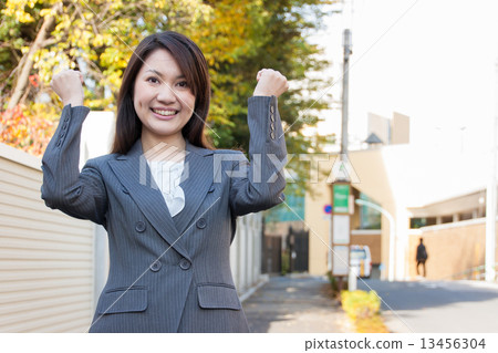 A female employee who performs a guts pose outdoors A female employee who performs a guts pose outdoors 13456304