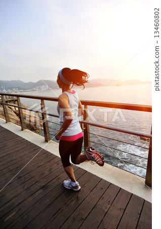 healthy lifestyle sports woman running on wooden boardwalk seaside  13460802