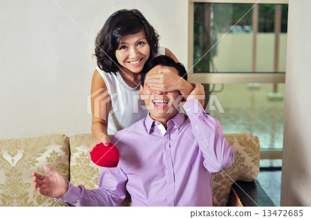 A beautiful Asian lady surprise her lover / boyfriend / husband from behind with her token of love  13472685