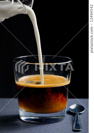 Pouring milk into a glass of black coffee Pouring milk into a glass of black coffee 13494542