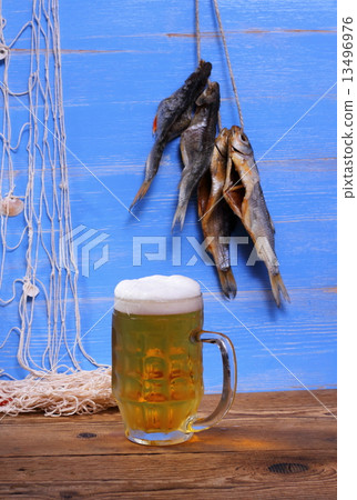 Mug of beer on blue background with dried rudd fish 13496976