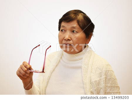 A woman in her 60s who takes off glasses 13499203