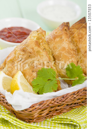 Samosas - Deep fried stuffed pasties with lemon wedges and dips  13507853