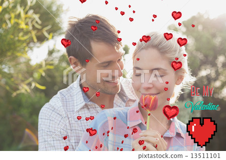 Composite image of young couple holding a flower in park Composite image of young couple holding a flower in park 13511101