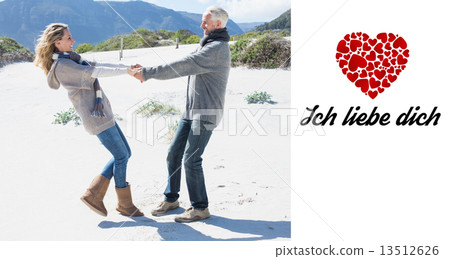 Composite image of smiling couple spinning on the beach in warm 13512626