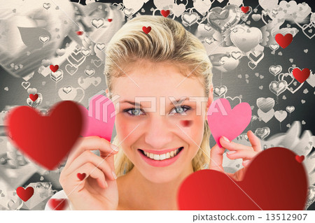 Composite image of attractive young blonde holding little hearts Composite image of attractive young blonde holding little hearts 13512907