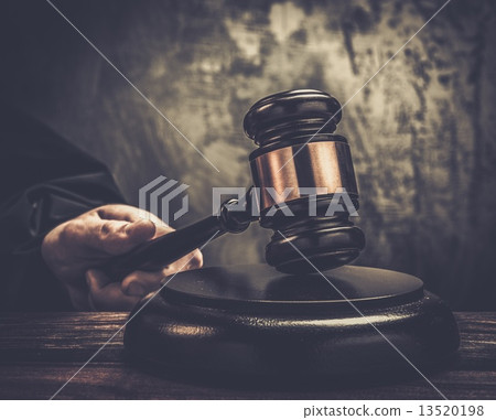 Judge's hand holding wooden hammer 13520198