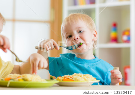 kid boy eating spaghetti in nursery 13520417