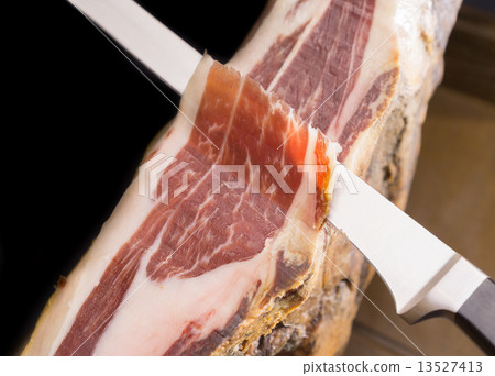 Top view of knife cutting Serrano ham, black background 13527413