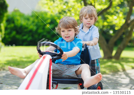 Two funny little boys having fun with race car outdoors Two funny little boys having fun with race car outdoors 13530115