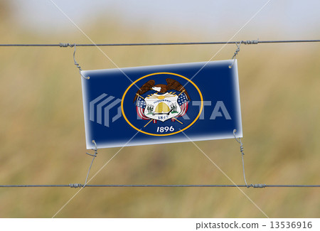 Border fence - Old plastic sign with a flag 13536916