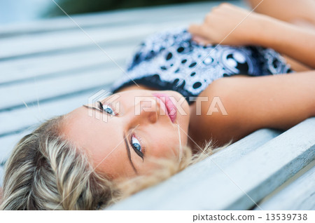 Portrait of a sexy young white blond woman posing on bench 13539738