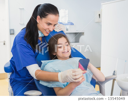Pediatric dentist and young patient holding a mirror 13545049
