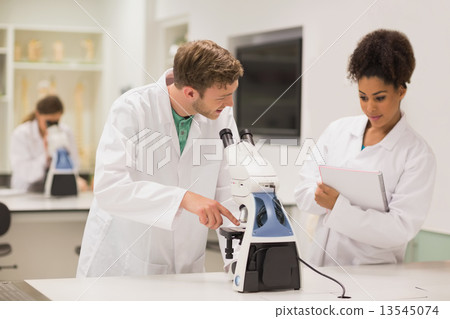Medical students working with microscope Medical students working with microscope 13545074