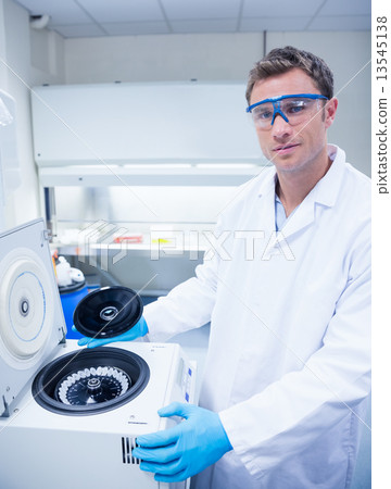 Chemist wearing safety glasses and using a centrifuge 13545138