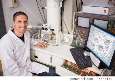Biochemistry student using large microscope and computer 13545139
