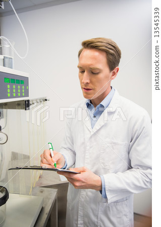 Pharmacist using machinery to make medicine Pharmacist using machinery to make medicine 13545339