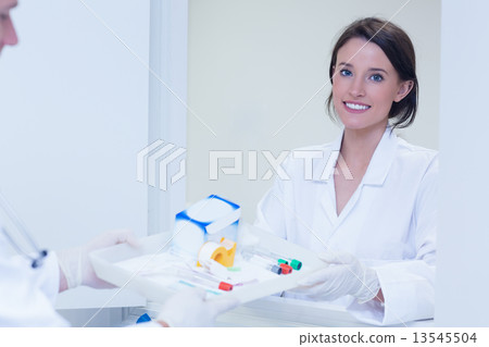 Portrait of a smiling woman taking tray with blood samples 13545504