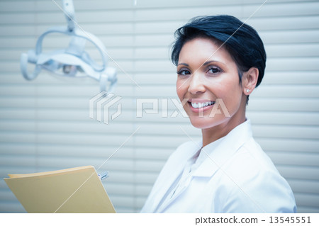 Smiling female dentist reading reports 13545551