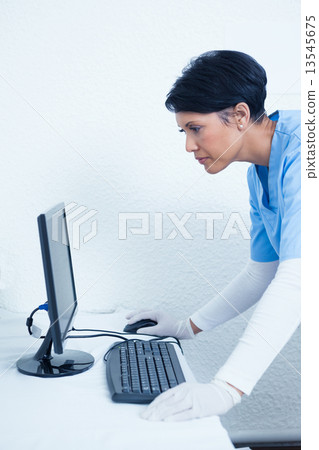 Female dentist looking at computer monitor Female dentist looking at computer monitor 13545675