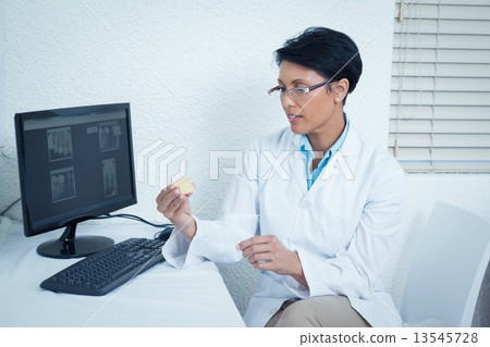 Dentist holding mouth model besides computer Dentist holding mouth model besides computer 13545728