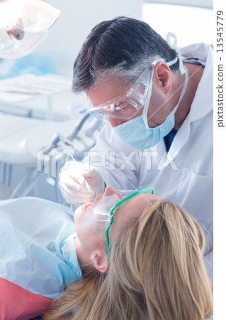 Dentist examining a patients teeth in the dentists chair 13545779