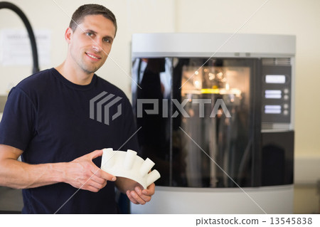 Engineering student holding object printed from 3d printer 13545838