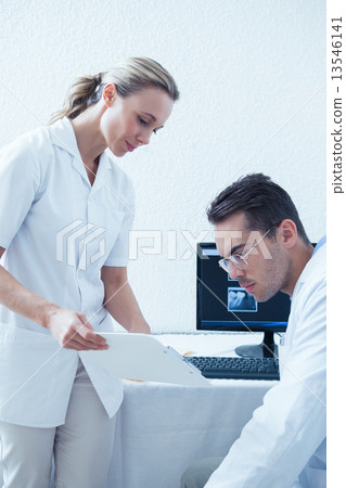 Side view of dentists discussing reports Side view of dentists discussing reports 13546141