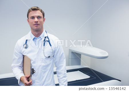 Happy doctor smiling at camera holding clipboard Happy doctor smiling at camera holding clipboard 13546142
