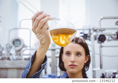 Stock Photo: Stylish brunette in denim jacket looking at beaker of beer