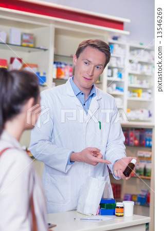 Pharmacist pointing a flask of pills in front of a customer 13546269