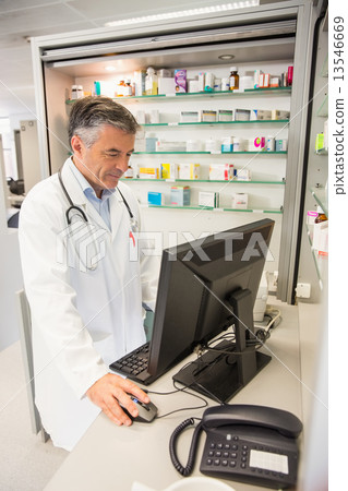 Senior pharmacist using the computer Senior pharmacist using the computer 13546669