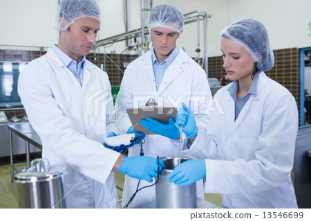 Man writing on clipboard while colleagues testing product 13546699