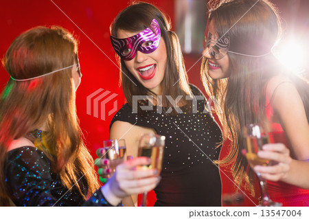 Friends in masquerade masks drinking champagne 13547004