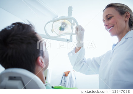 Female dentist examining mans teeth 13547058