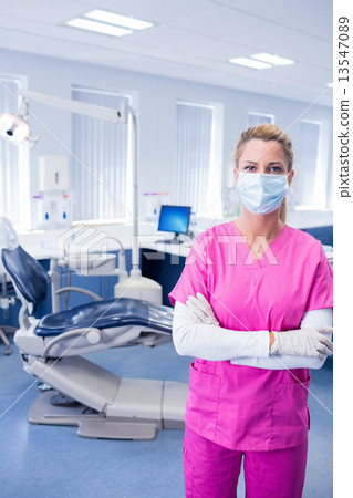Dentist in pink scrubs standing with arms folded Dentist in pink scrubs standing with arms folded 13547089