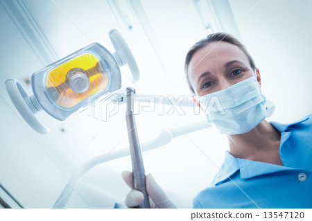 Female dentist in surgical mask holding dental tool Female dentist in surgical mask holding dental tool 13547120