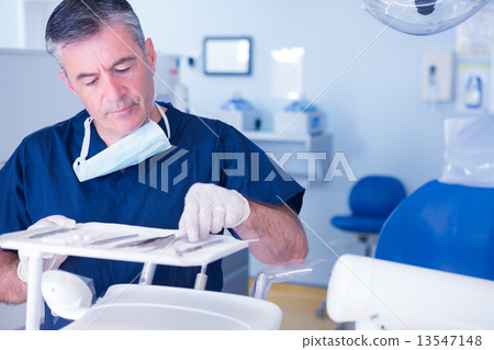 Focused dentist picking up tool 13547148