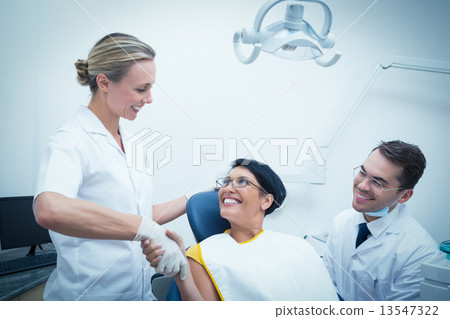 Female dentist shaking hands with woman 13547322