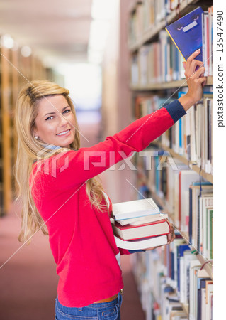 Mature student picking out book in library Mature student picking out book in library 13547490