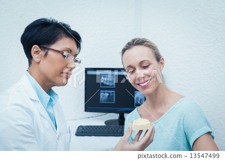 Dentist showing woman prosthesis teeth 13547499