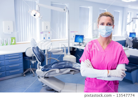 Dentist in surgical mask standing with arms folded Dentist in surgical mask standing with arms folded 13547774