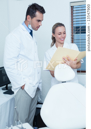 Smiling dentists discussing reports Smiling dentists discussing reports 13547900