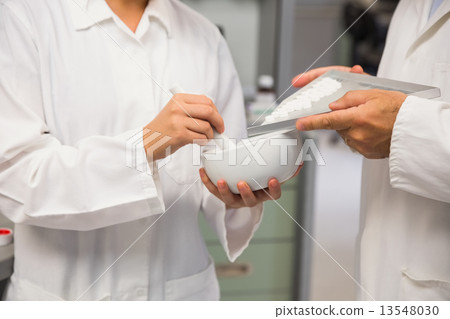Junior pharmacist mixing a medicine with her senior 13548030